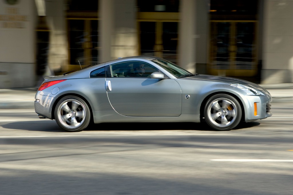 Silver Nissan 350Z Coupe cornering dynamically on city streets showing its planted stance and wide track