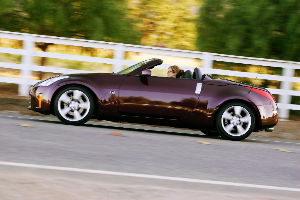 Nissan 350Z Roadster convertible in motion top-down showing its athletic profile and dual-fairing tonneau cover
