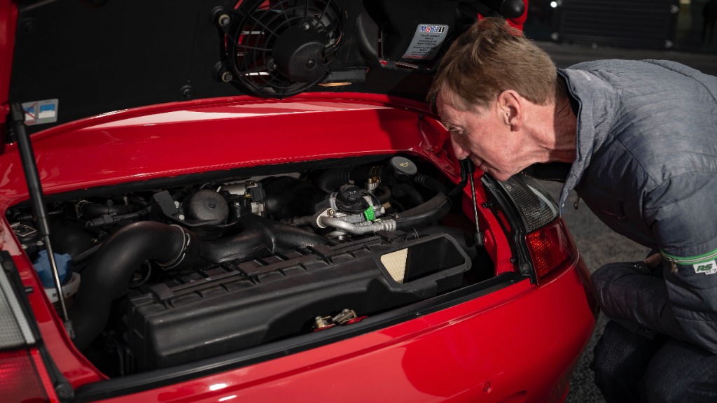 Legendary test driver Walter Röhrl inspecting the engine bay of the Porsche 996 Turbo
